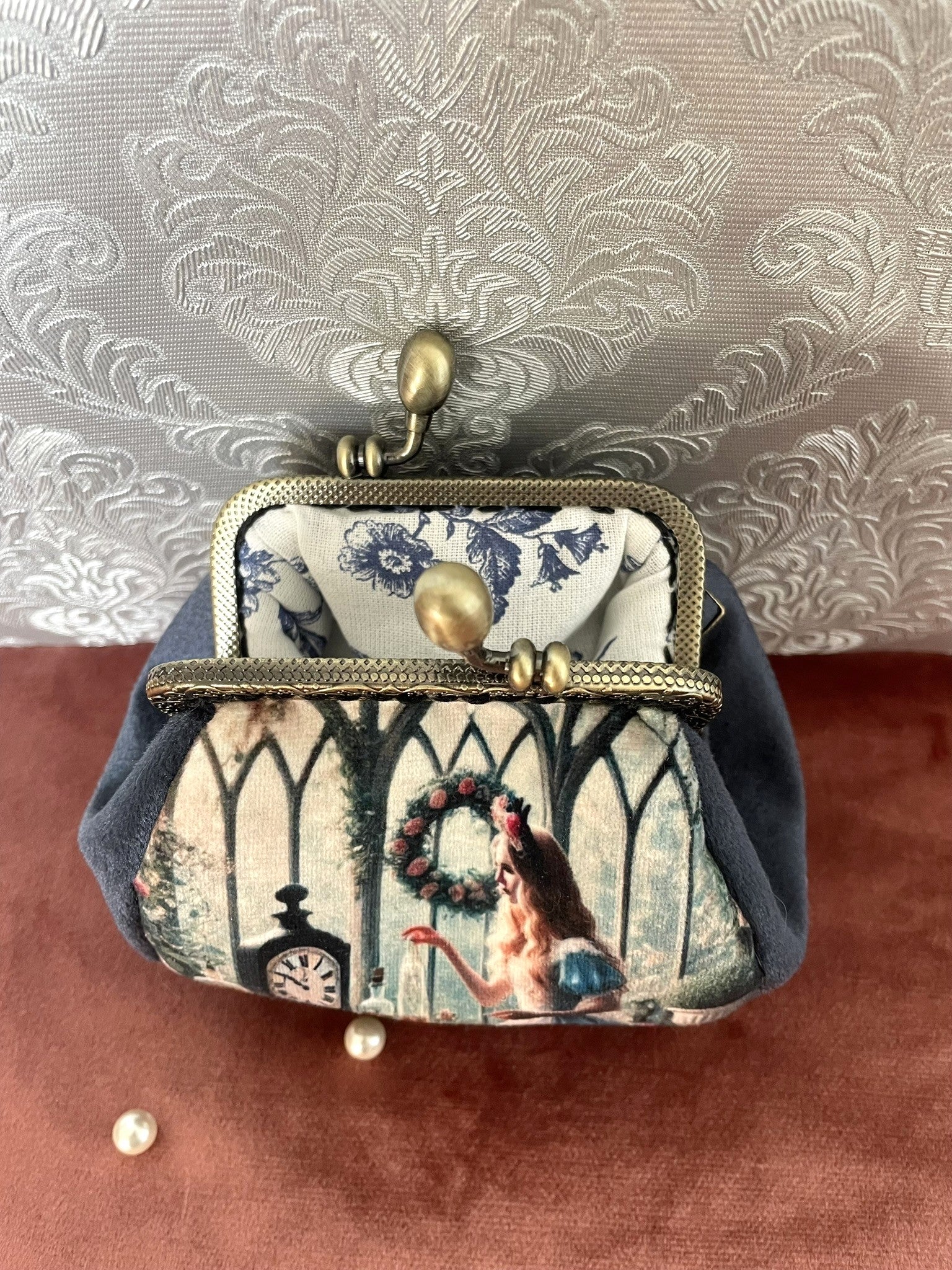 Vue intérieure du porte-monnaie montrant la doublure fleurie bleue délicate et le cadre métallique rétro.