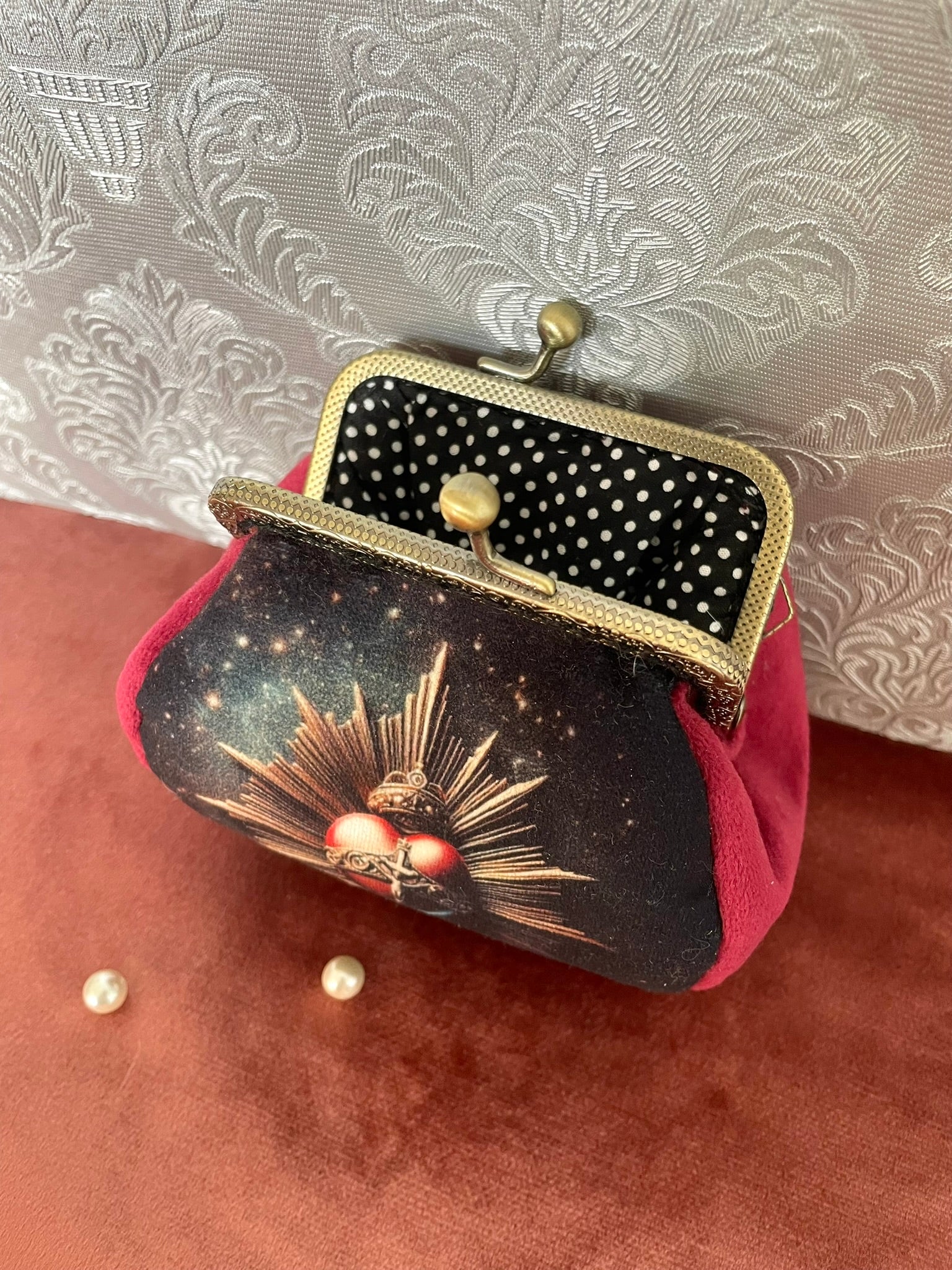 Vue intérieure du porte-monnaie montrant la doublure noire à pois blancs et le cadre métallique rétro.