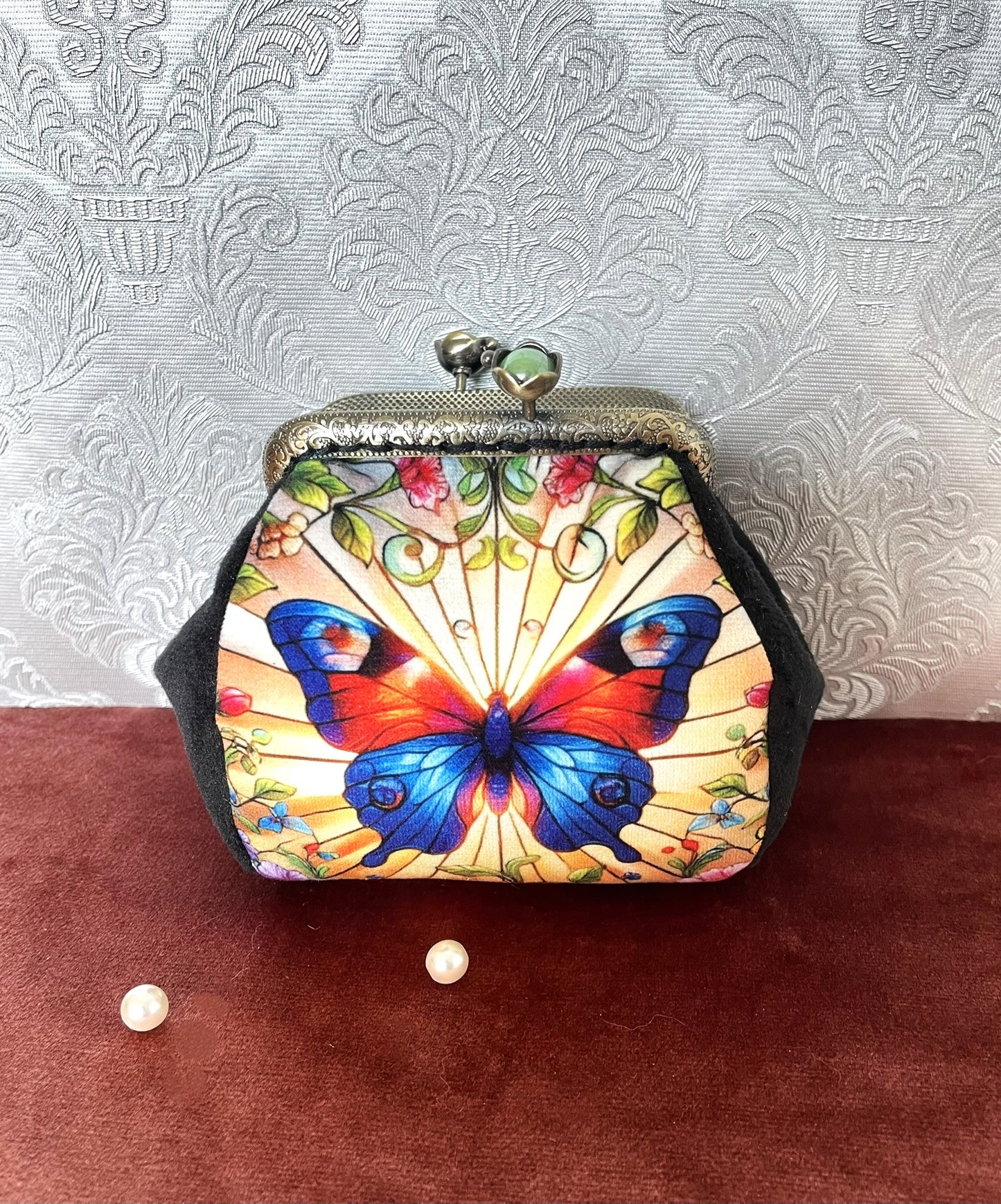 Porte-monnaie rétro avec illustration de papillon style vitrail rouge et bleu vif et côtés en velours noir, création artisanale.