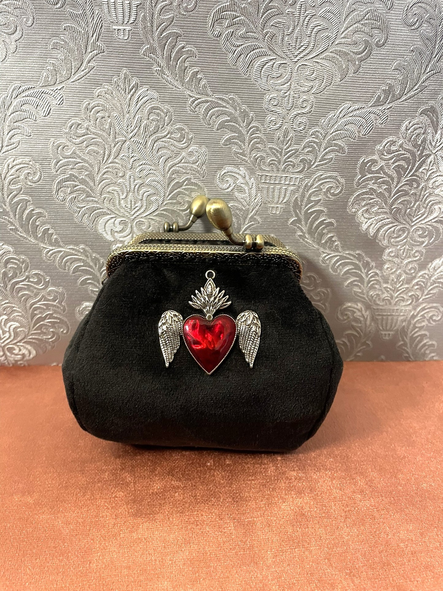 Porte-monnaie rétro femme en velours noir avec bijou exvoto cœur sacré ailé rouge.