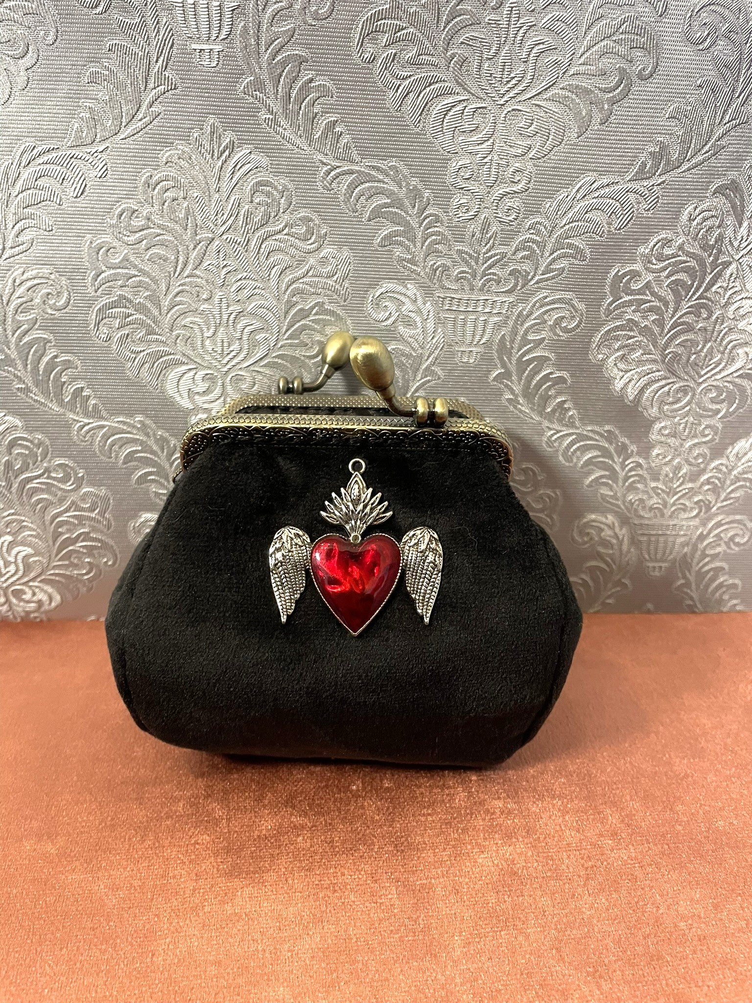 Porte-monnaie rétro femme en velours noir avec bijou exvoto cœur sacré ailé rouge.
