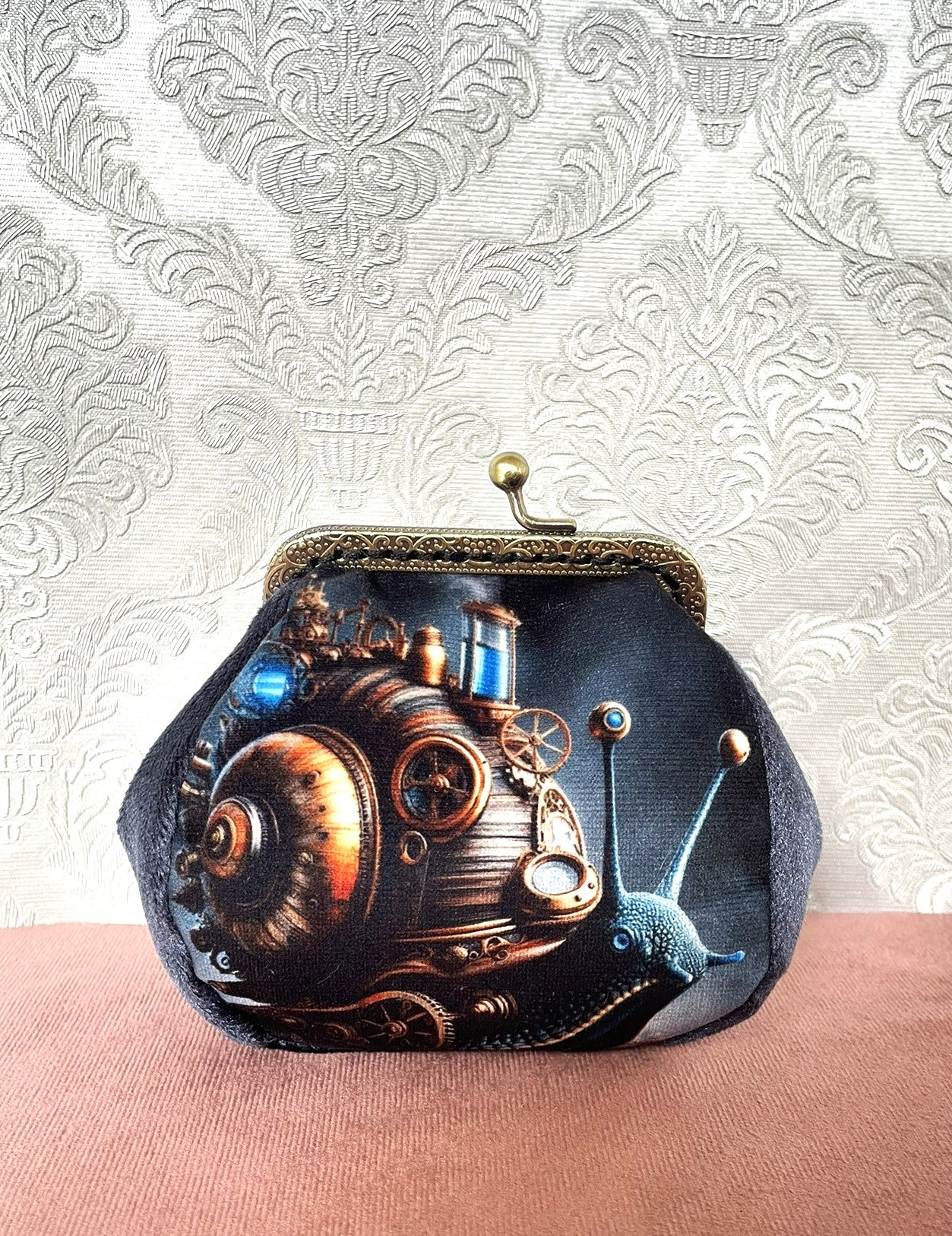 Porte-monnaie vintage steampunk avec illustration d'escargot mécanique sur velours sombre.