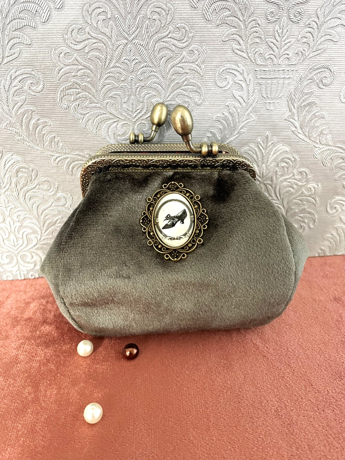 Porte-monnaie artisanal en velours vert-de-gris avec un médaillon central escarpin et un fermoir en bronze ciselé.