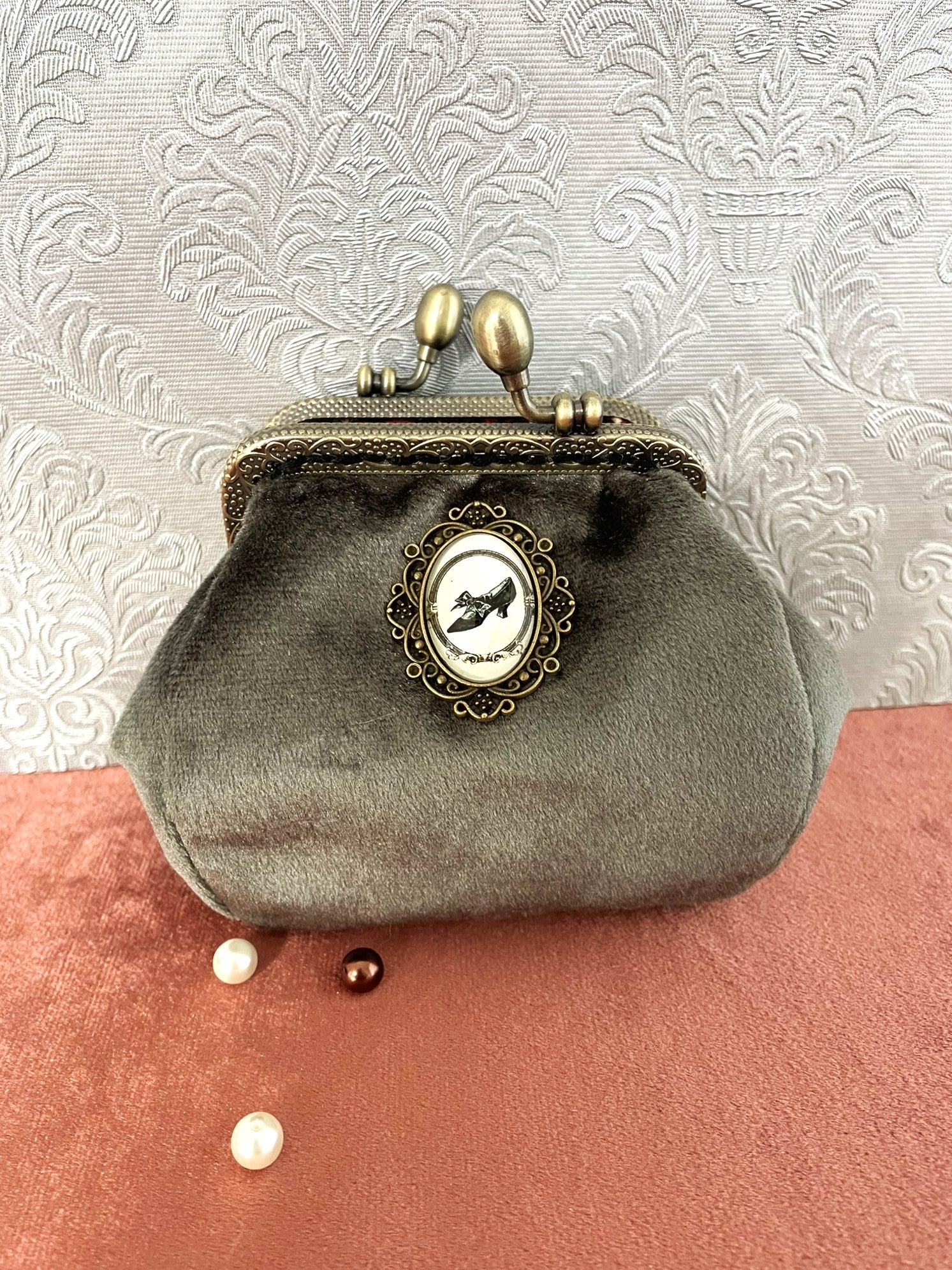 Porte-monnaie artisanal en velours vert-de-gris avec un médaillon central escarpin et un fermoir en bronze ciselé.