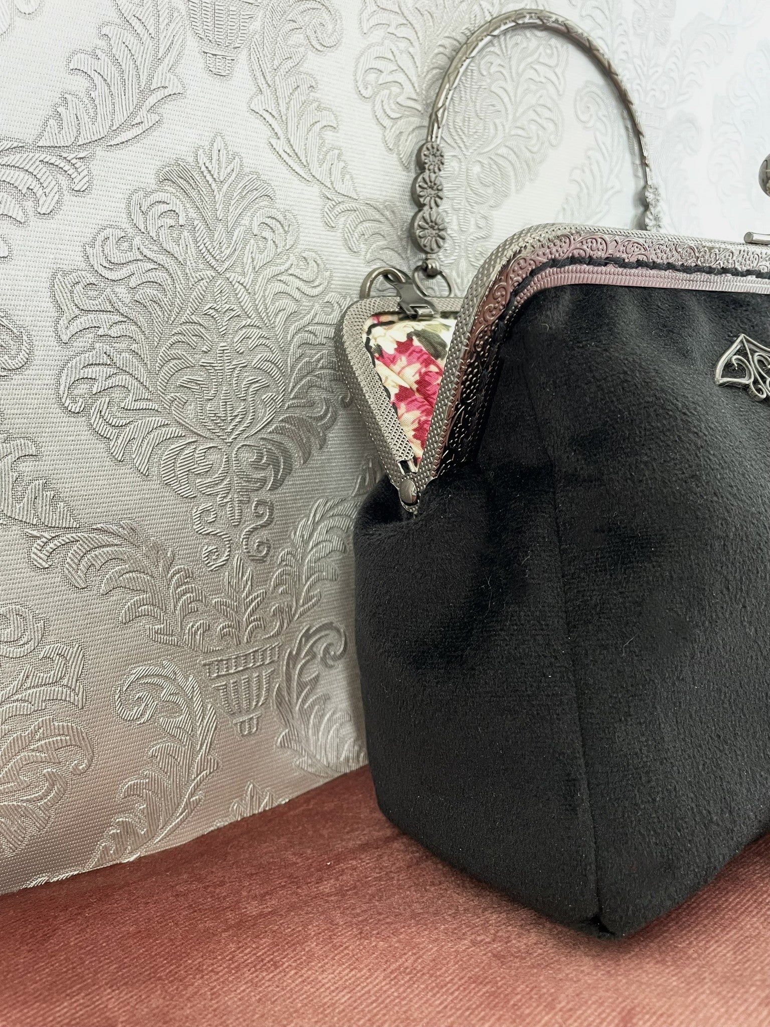 Détail de profil d'un sac à main artisanal en velours noir de qualité avec armature métallique rétro ciselée.