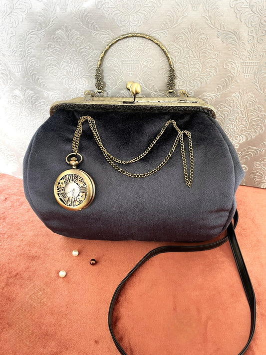 Sac à main en velours bleu nuit avec une montre à gousset dorée suspendue à une chaîne.