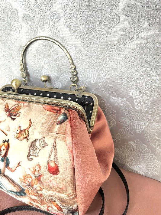 Côté en velours rose poudré doux et détails du fermoir métallique à poignée effet bronze sur un sac de créateur.