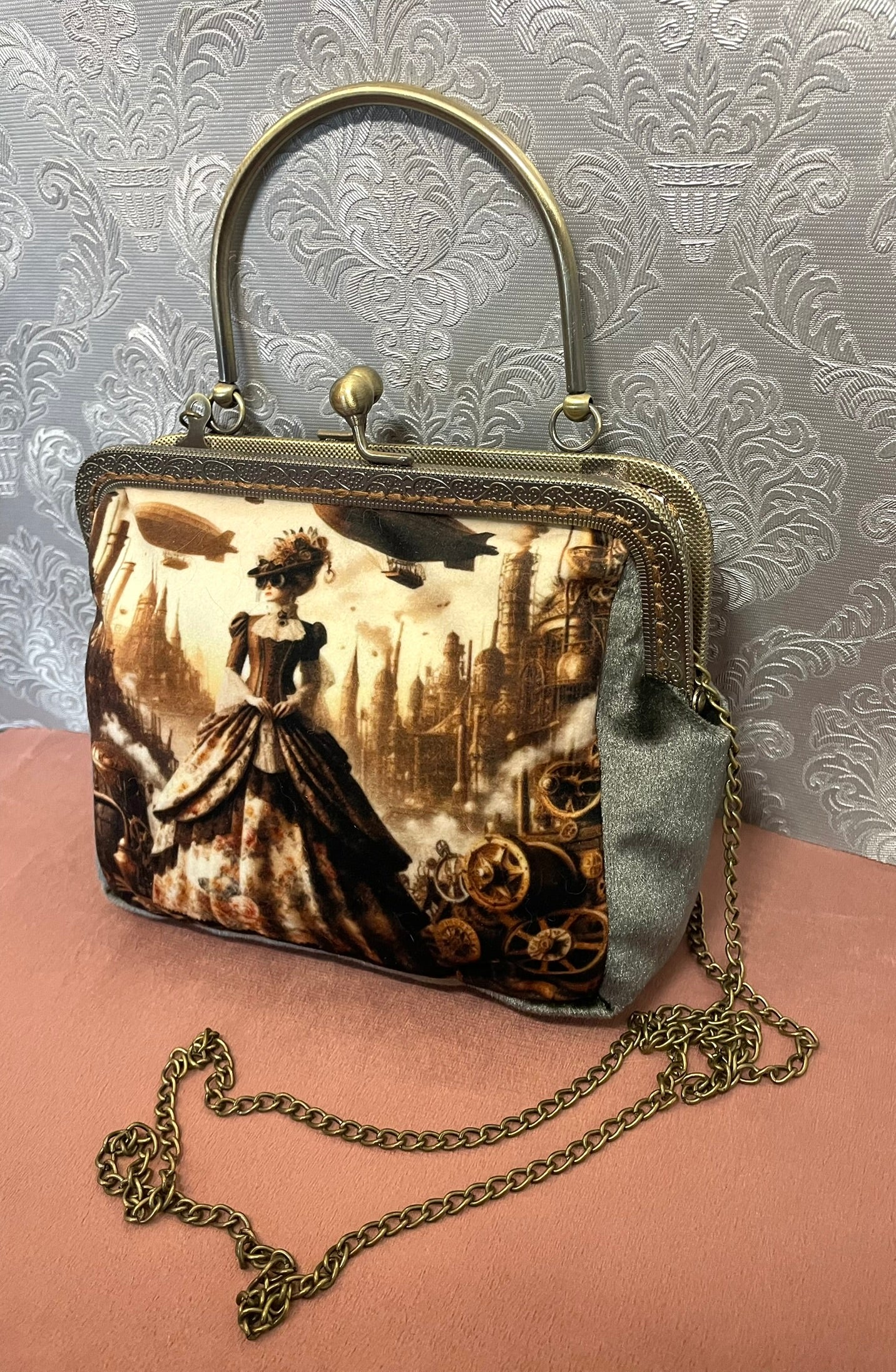 Sac avec poignée rigide et chaîne bandoulière en bronze.