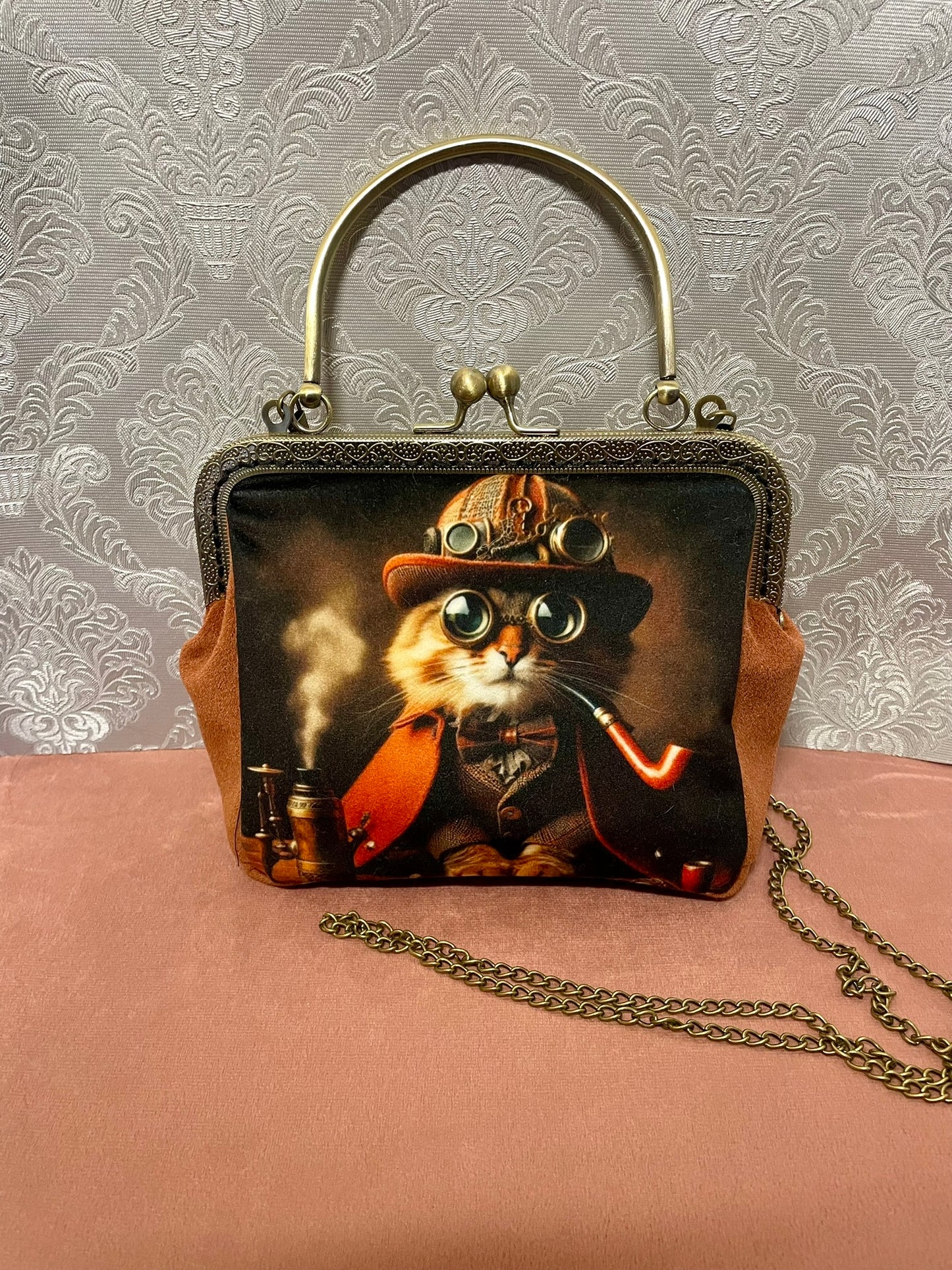 Sac bandoulière chat gentleman avec chaîne gourmette en métal effet bronze et poignée rigide.