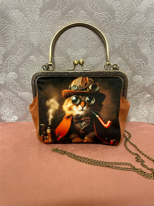 Sac bandoulière chat gentleman avec chaîne gourmette en métal effet bronze et poignée rigide.