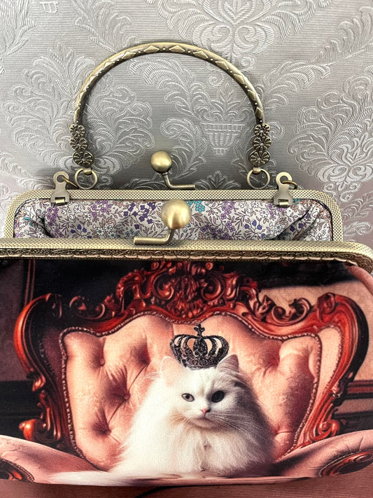 Sac à main rétro en tissu et velours vieux rose avec bandoulière, illustrant un chat blanc majestueux couronné sur un fauteuil baroque - Création Le Comptoir de Suzanne.