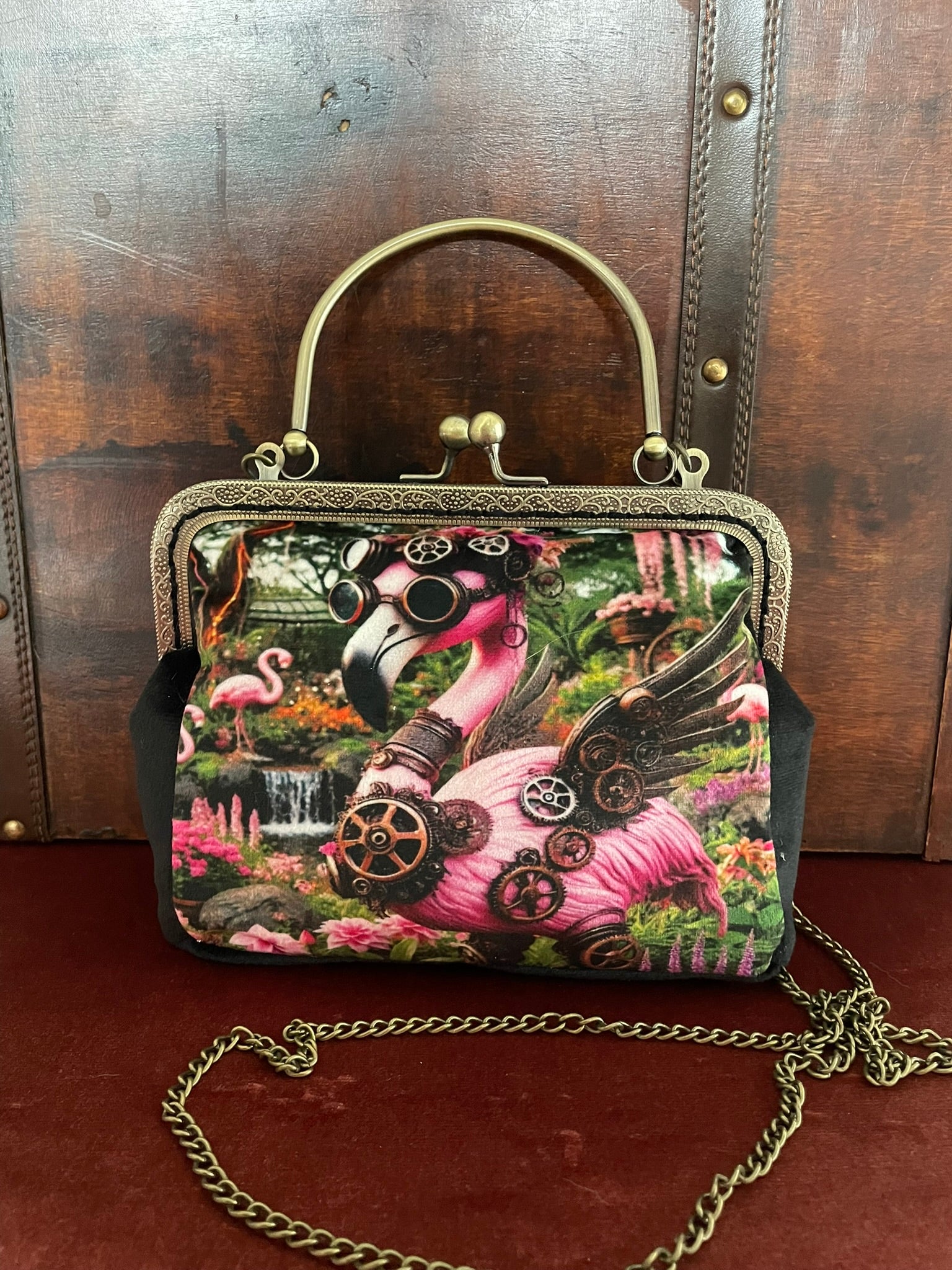 Sac flamant rose avec sa chaîne bandoulière en métal bronze vieilli.