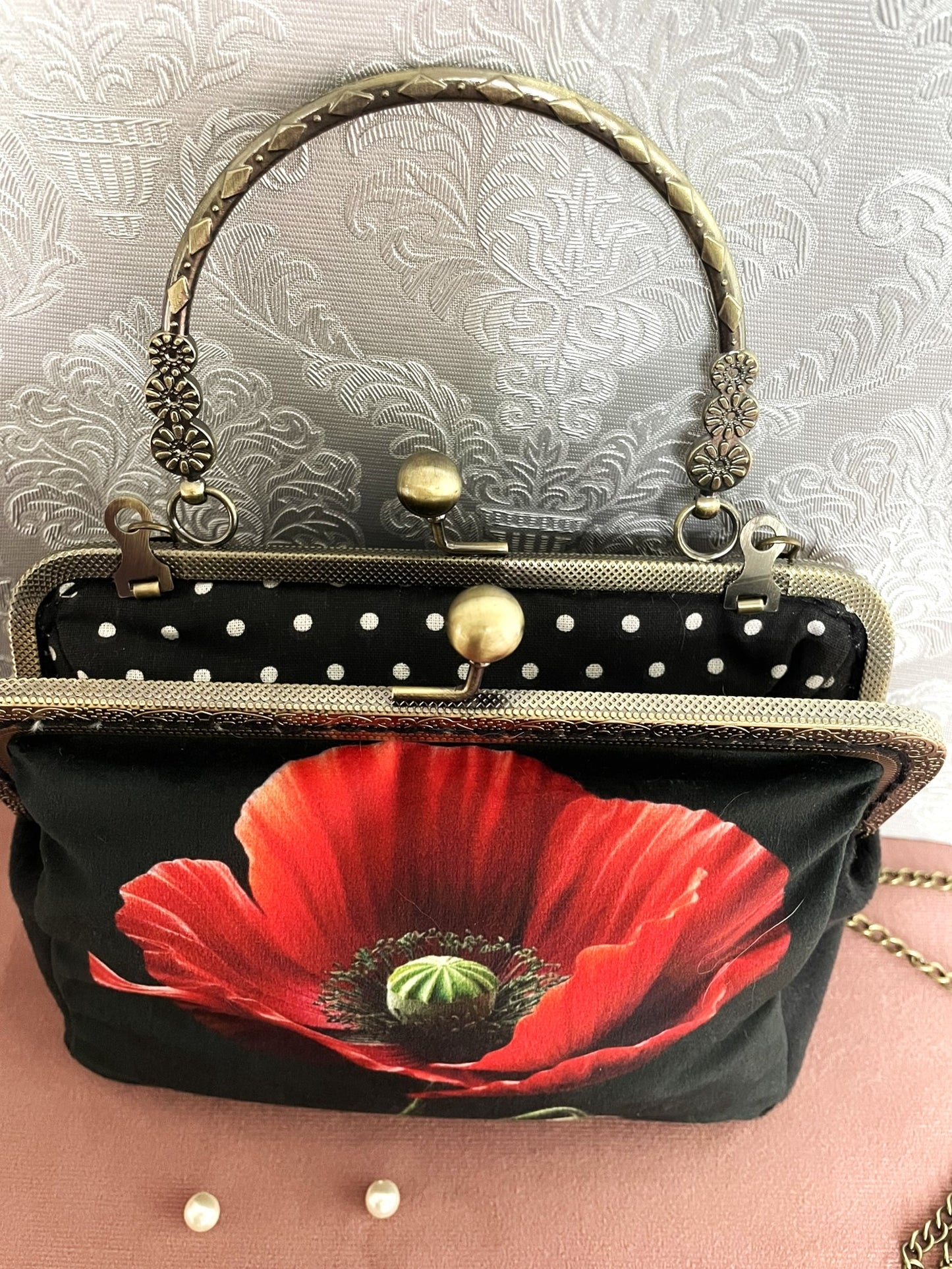 Vue du dessus du sac coquelicot ouvert montrant la doublure noire à pois blancs et le fermoir  clic-clac double boule.