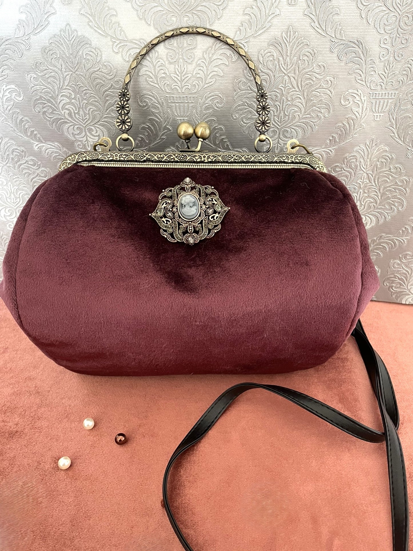 Sac à main vintage en velours prune avec broche camée centrale et fermoir bronze.