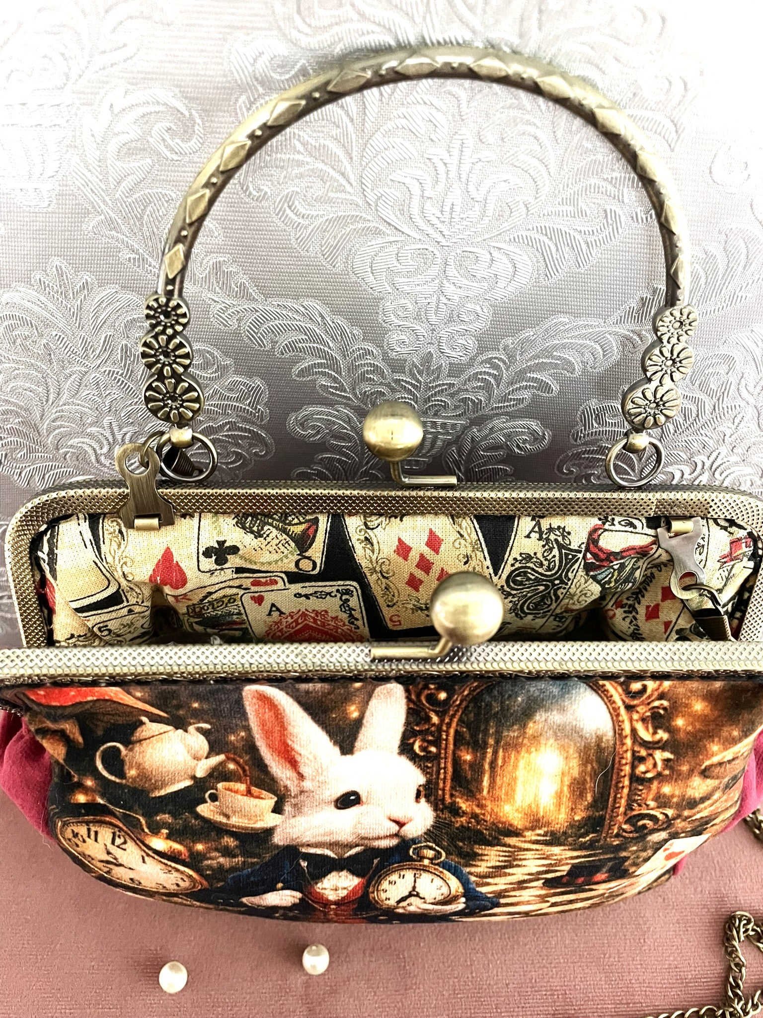 Sac à main clic-clac vintage ouvert montrant une magnifique doublure intérieure en coton illustrée de cartes à jouer rétro (as de pique, roi de cœur).