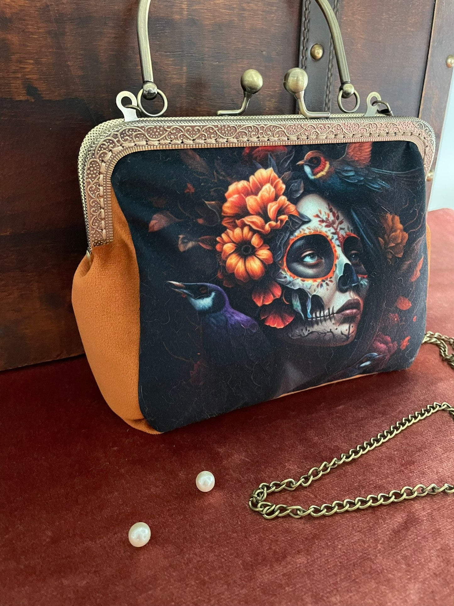 Vue de profil du sac montrant le velours safran et la chaîne bandoulière bronze.