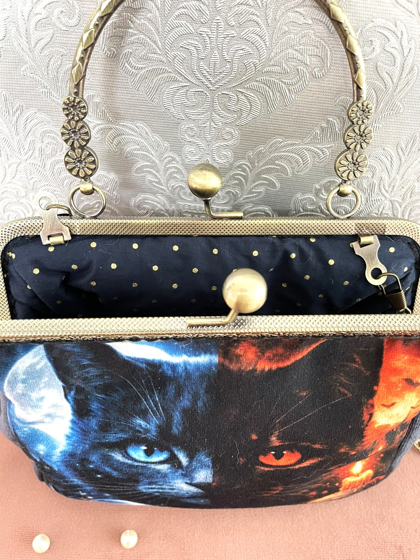 Intérieur ouvert du sac gothique chat révélant une doublure premium en coton bleu marine parsemée de pois dorés et le fermoir esprit vintage.
