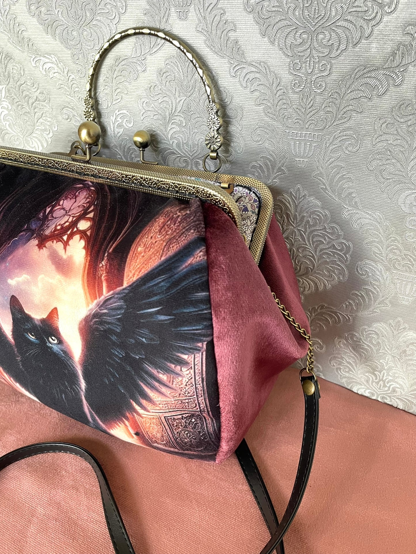 Soufflet en velours lie de vin et détails du fermoir métallique à poignée effet bronze sur un sac de créateur.
