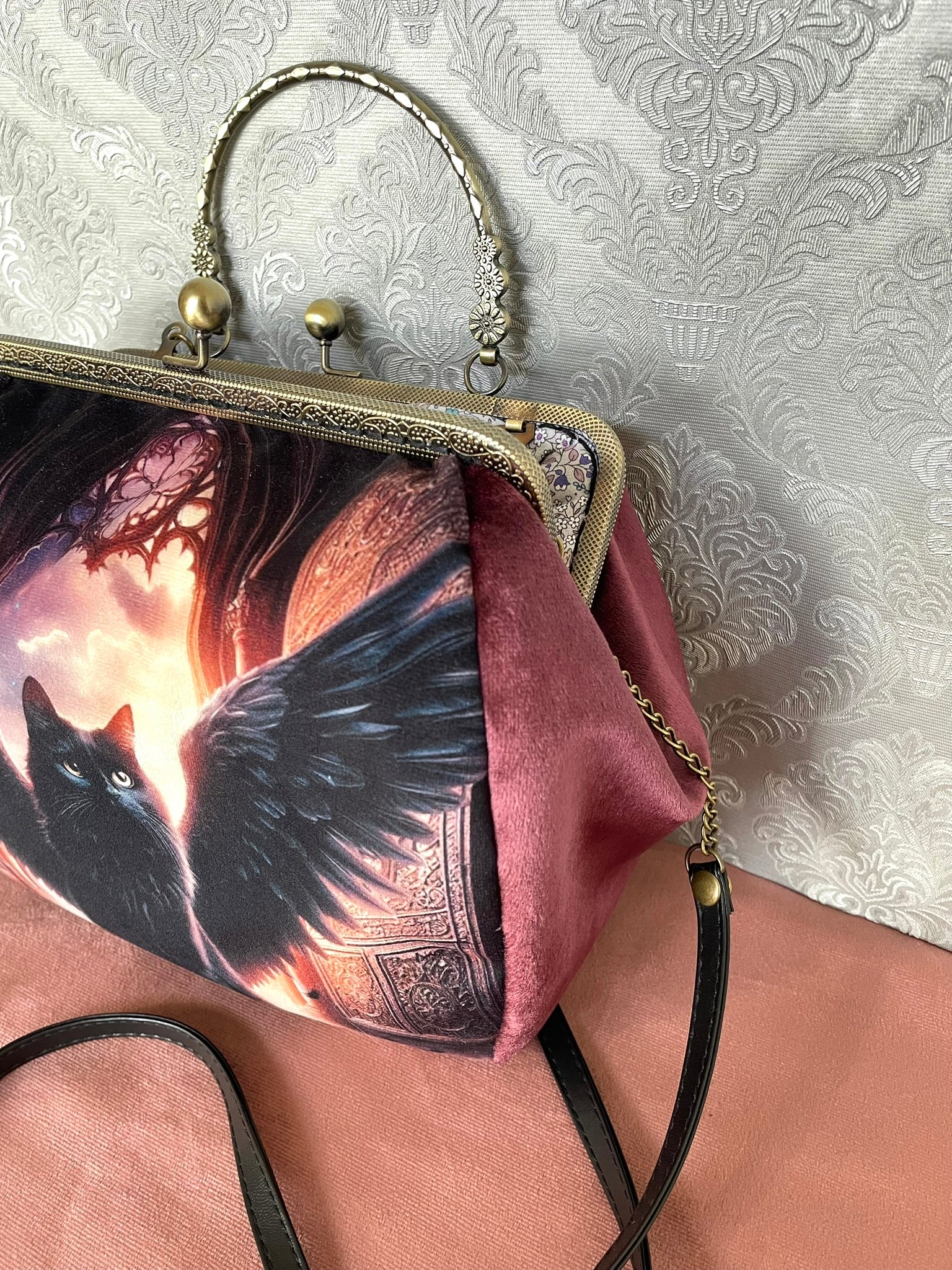 Soufflet en velours lie de vin et détails du fermoir métallique à poignée effet bronze sur un sac de créateur.