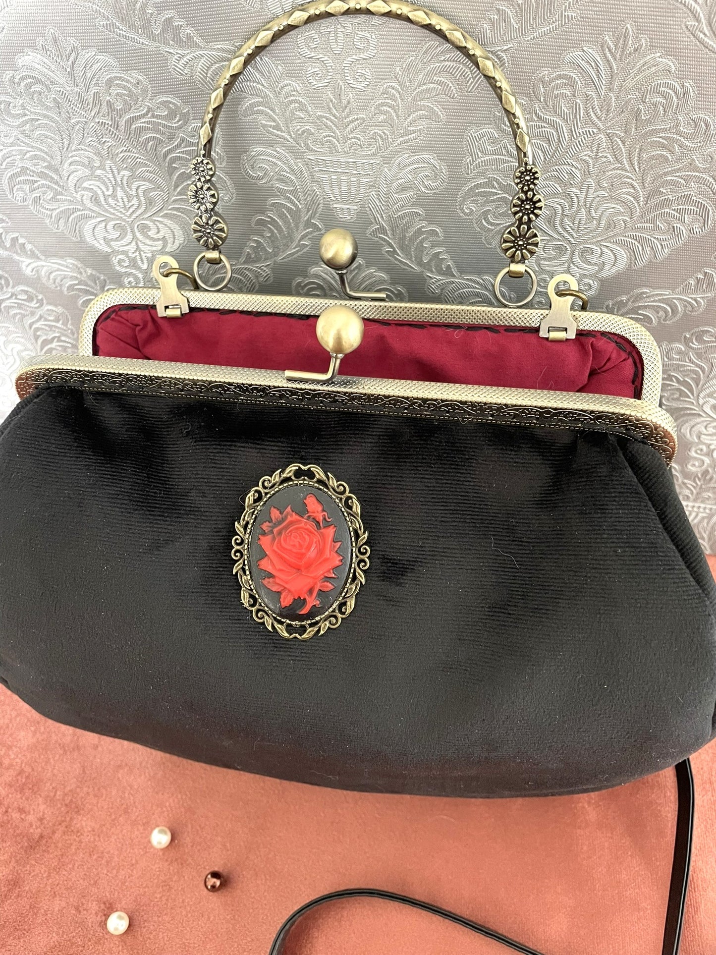 Intérieur du sac gothique ouvert, révélant une doublure en satin rouge contrastante et le fermoir bronze.