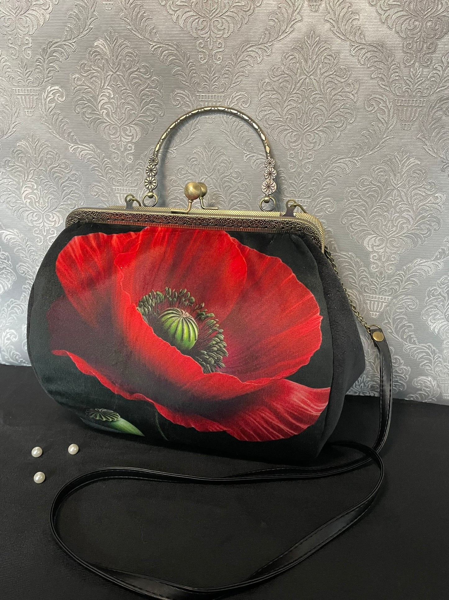 Sac à main noir de créateur avec une grande fleur de coquelicot rouge.