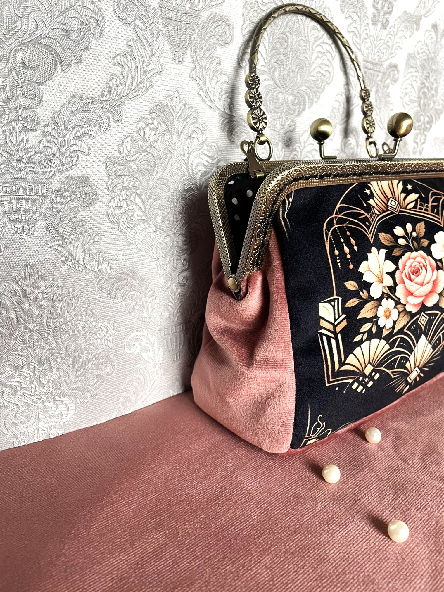 Vue de face du sac bandoulière de style Art Déco avec motif de rose ancienne, anse rigide travaillée et chaîne dorée amovible.