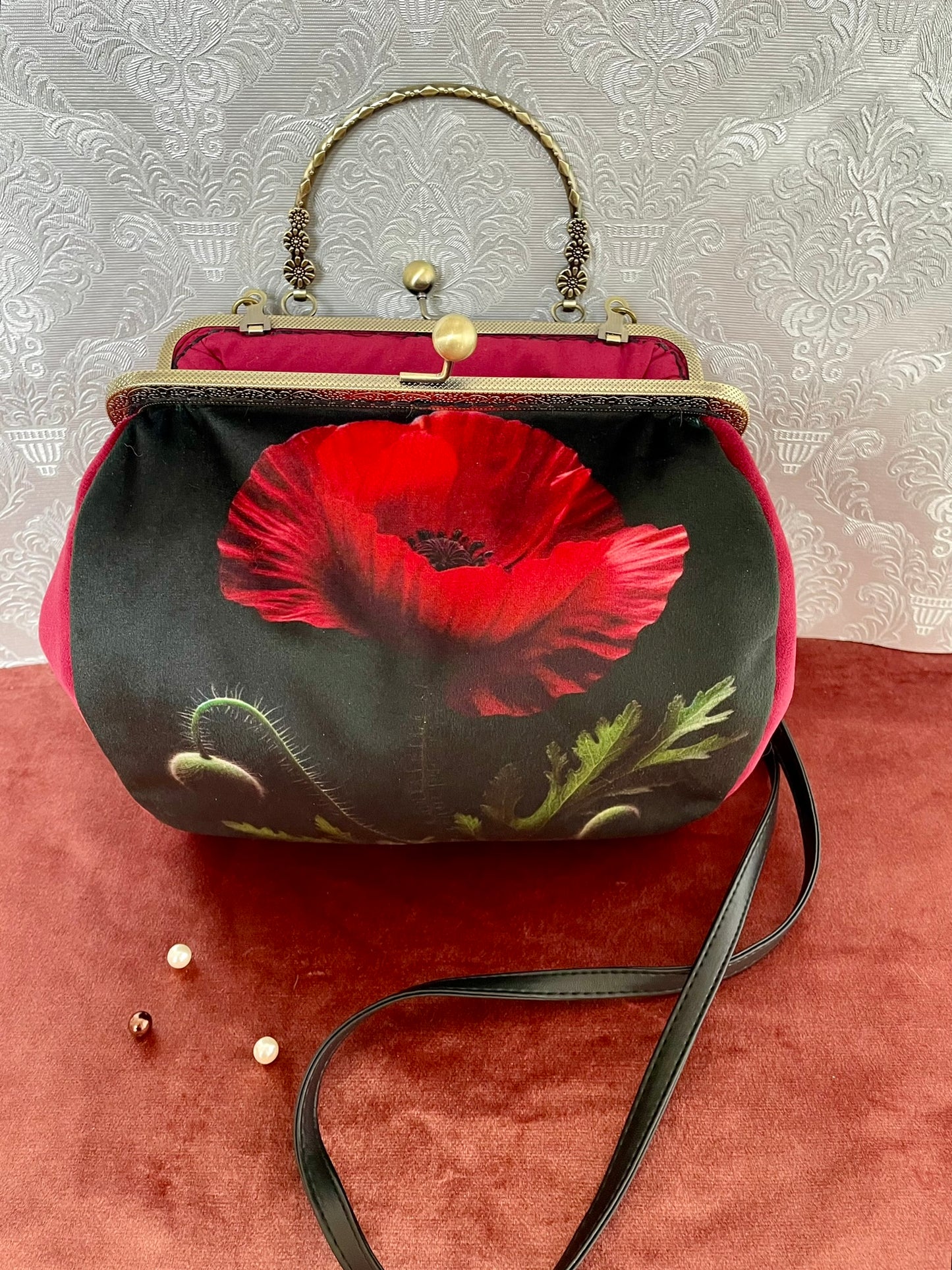 Sac à main vintage en velours avec grande broderie coquelicot rouge vif, posé sur velours rouge.