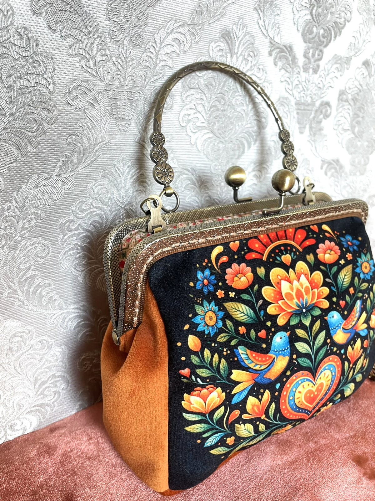 Vue trois-quarts sac pochette retro velours terracotta orange motif folklorique oiseaux et fleurs