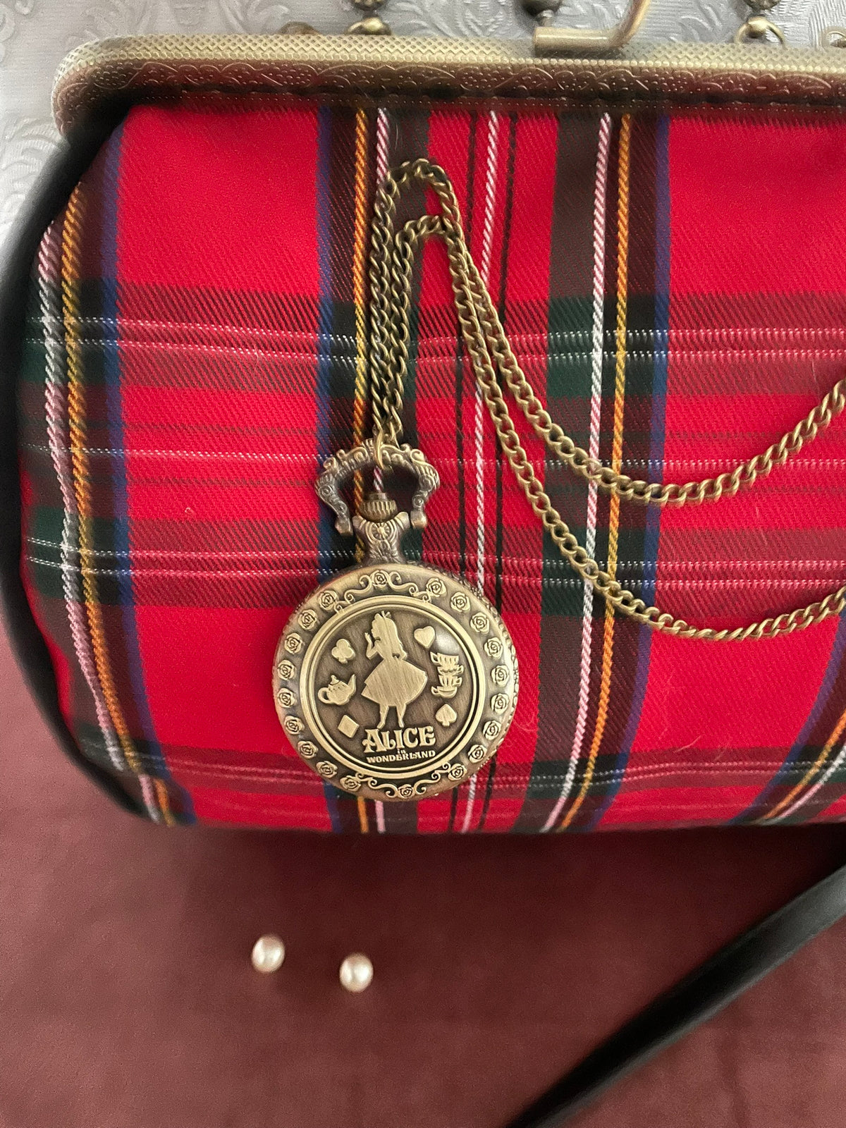 Gros plan du pendentif montre à gousset Alice au Pays des Merveilles sur tartan écossais Le Comptoir de Suzanne