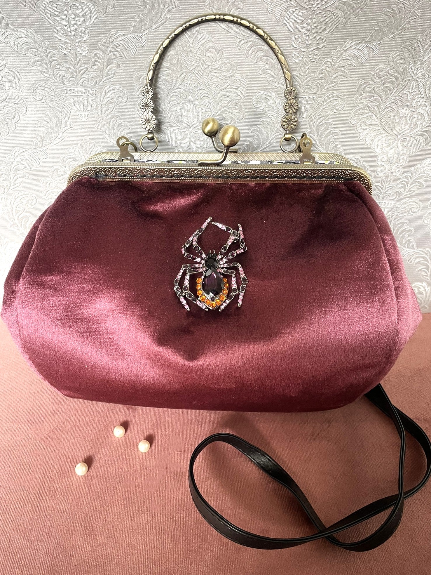 Sac à main rétro chic en velours bordeaux avec bijou araignée scintillante et bandoulière noire - Le Comptoir de Suzanne.