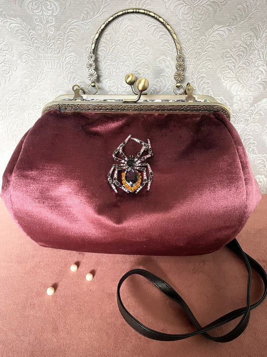 Sac à main rétro chic en velours bordeaux avec bijou araignée scintillante et bandoulière noire - Le Comptoir de Suzanne.
