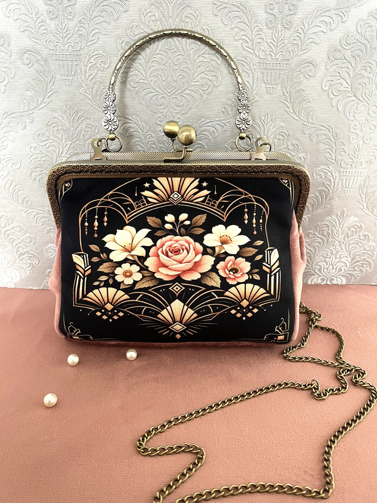 Gros plan latéral d'un sac rétro en velours rose poudré avec motif floral style Art Déco et fermoir baiser vintage en bronze.