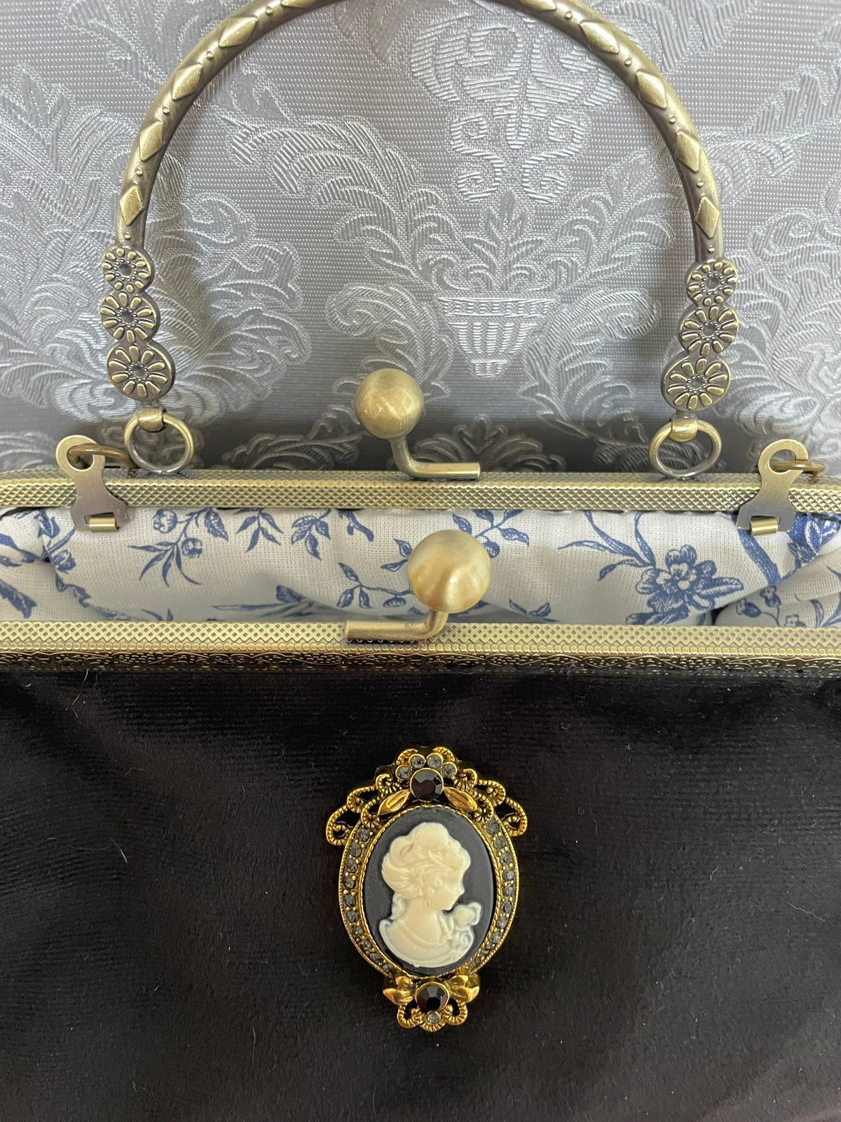 Vue rapprochée du fermoir couleur bronze ouvert et doublure coton bleue fleurs Toile de Jouy sac noir Le Comptoir de Suzanne