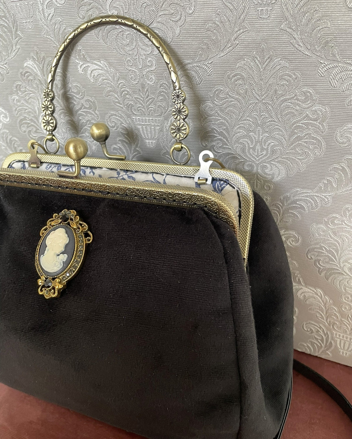 Vue de trois-quarts sac rétro en velours noir avec bijou camée et fermoir bronze Le Comptoir de Suzanne