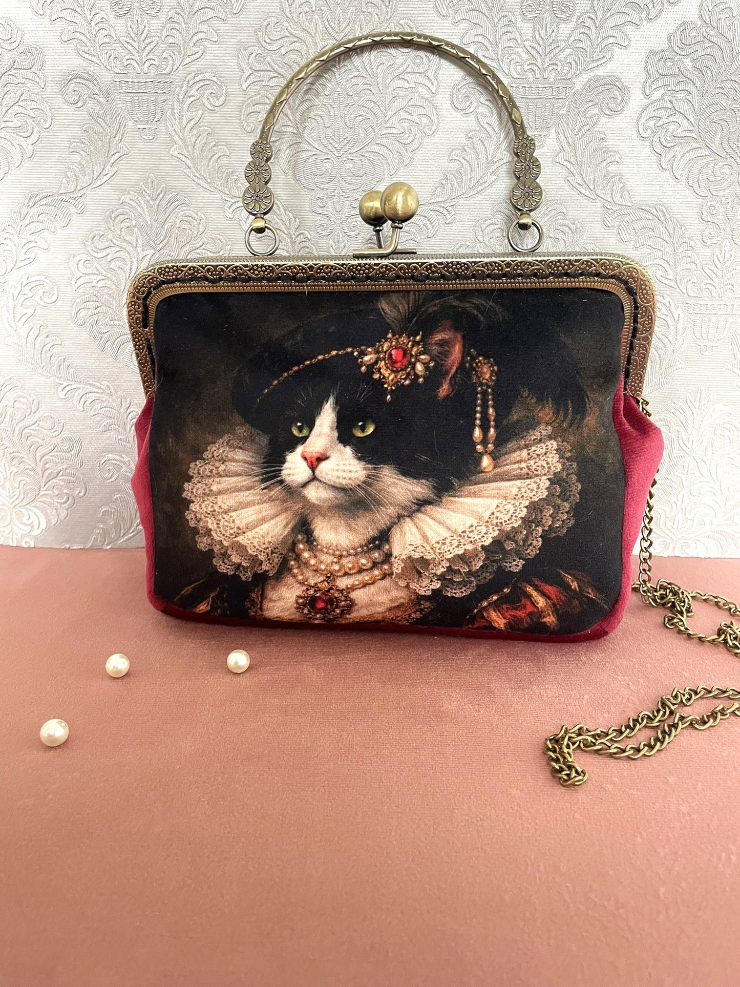 Sac pochette rétro vintage en velours bordeaux et illustration de chat noir et blanc en costume de la Renaissance avec collerette de dentelle et bijoux princiers.