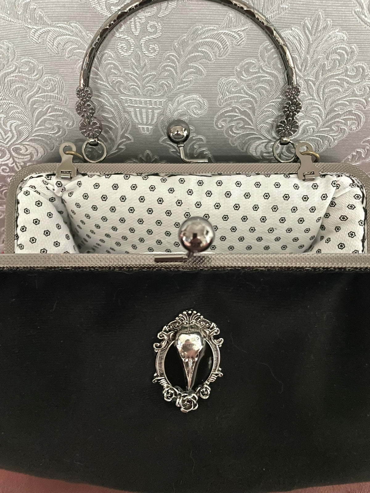 Vue rapprochée du médaillon crâne de corbeau et de la doublure coton géométrique du sac Le Comptoir de Suzanne