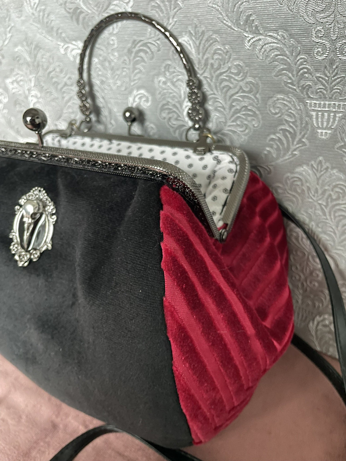 Vue de trois-quarts du sac rétro en velours noir et rouge avec médaillon crâne de corbeau Le Comptoir de Suzanne