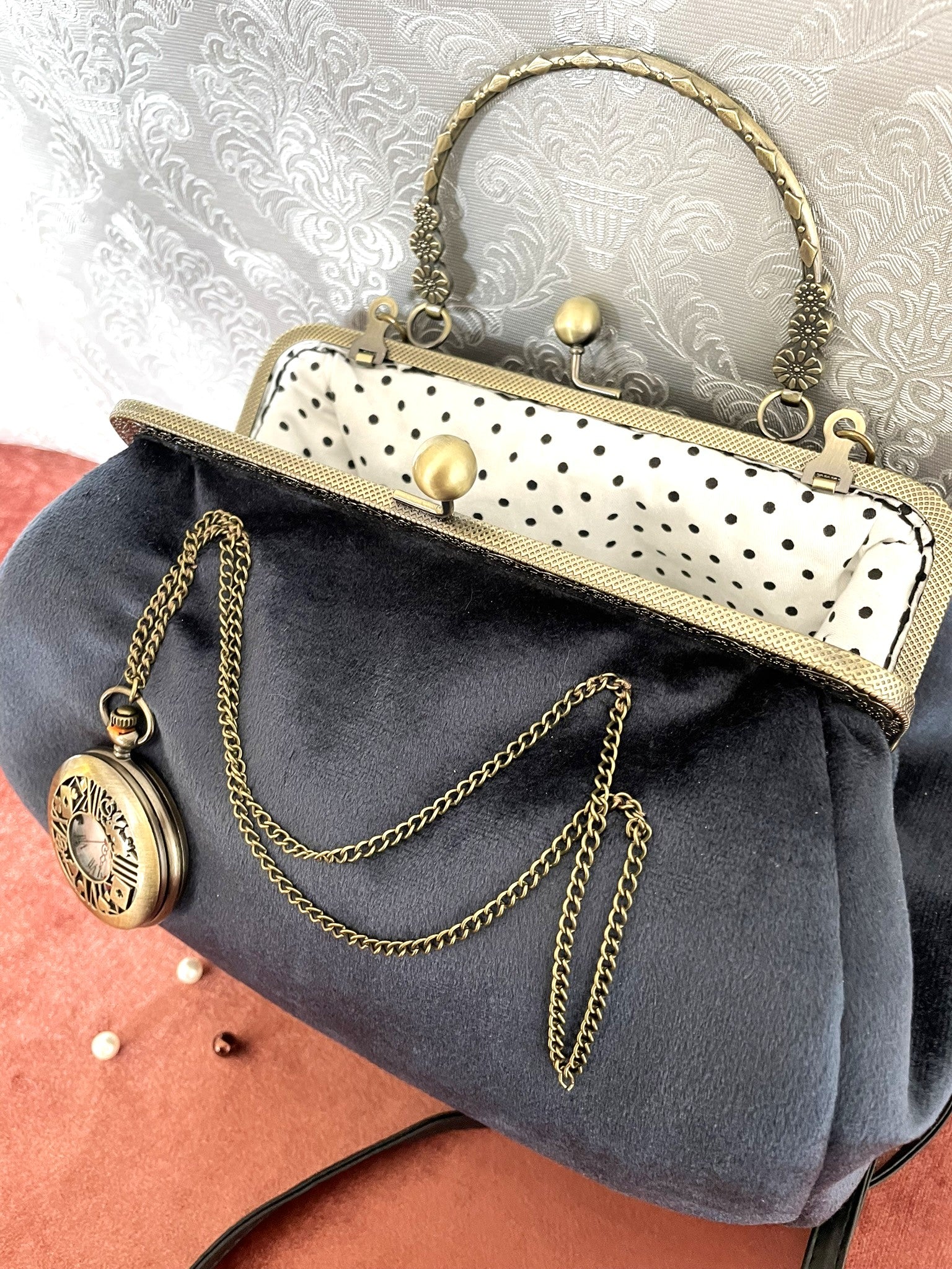 ntérieur du sac ouvert révélant une doublure blanche à pois noirs et un fermoir métallique bronze.