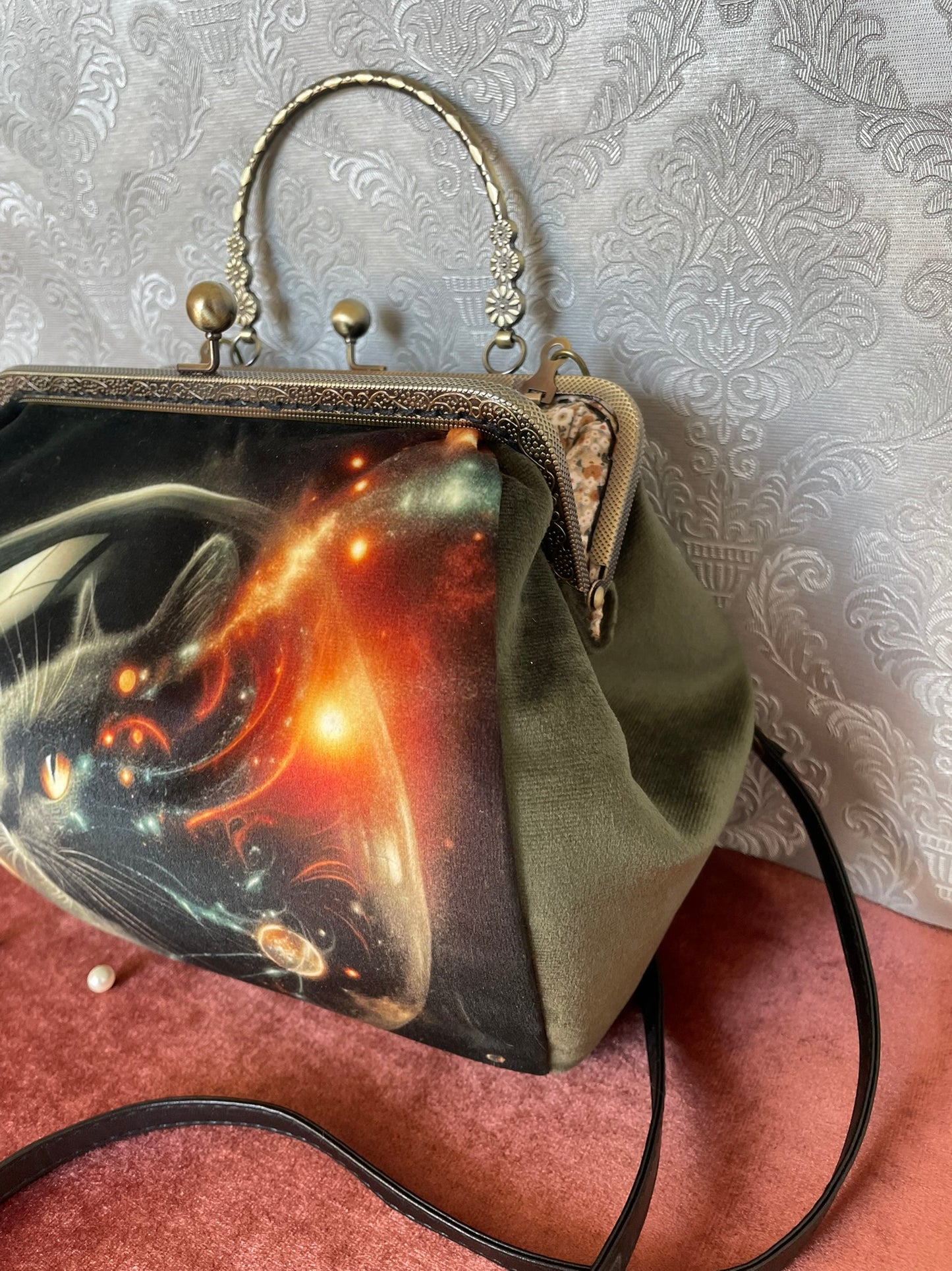 Vue de profil d'un sac rétro en velours vert montrant le fermoir effet bronze vieilli et la poignée travaillée.