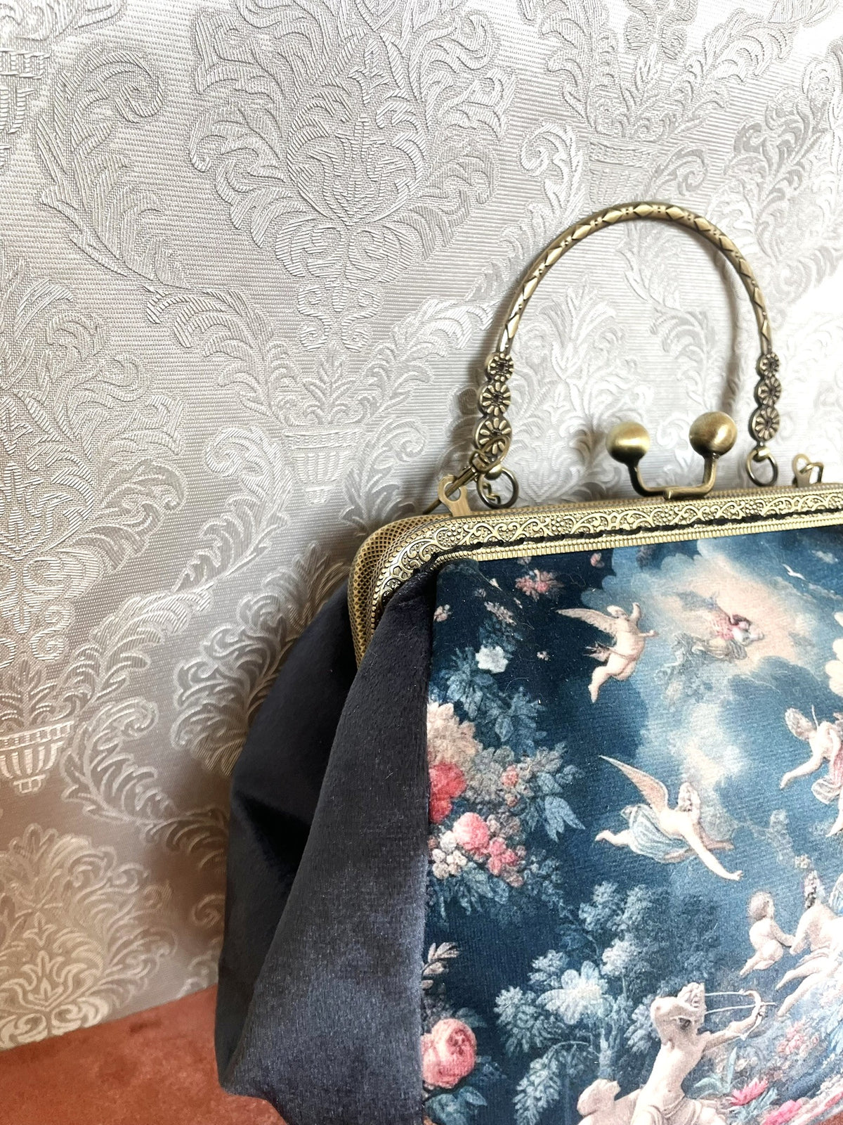 Gros plan fermoir bronze et poignee bijou d'un sac retro en velours motif anges