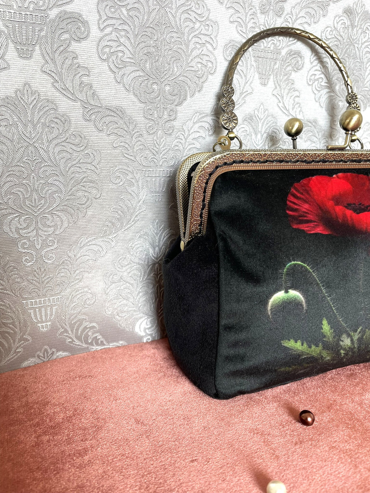 Vue de trois-quarts sac retro velours noir motif coquelicot botanique avec fermoir bronze