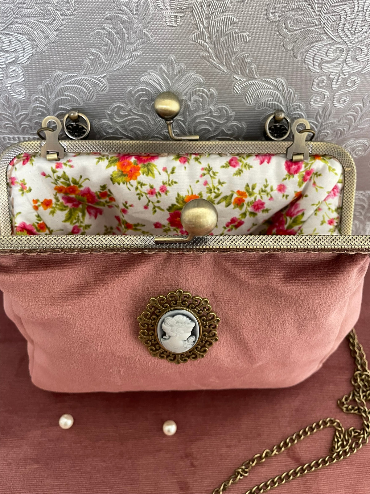 Gros plan fermoir effet bronze et doublure coton fleurie champetre d'une pochette clutch rose