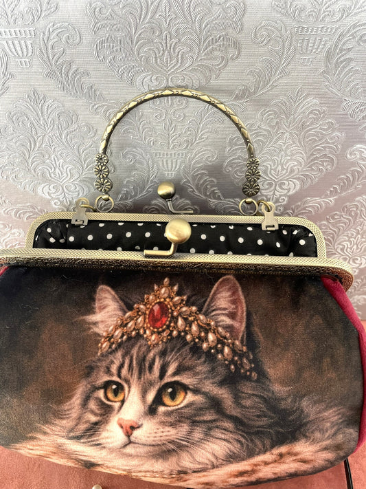 Gros plan velours rouge et fermoir bronze cisele d'un sac retro chat