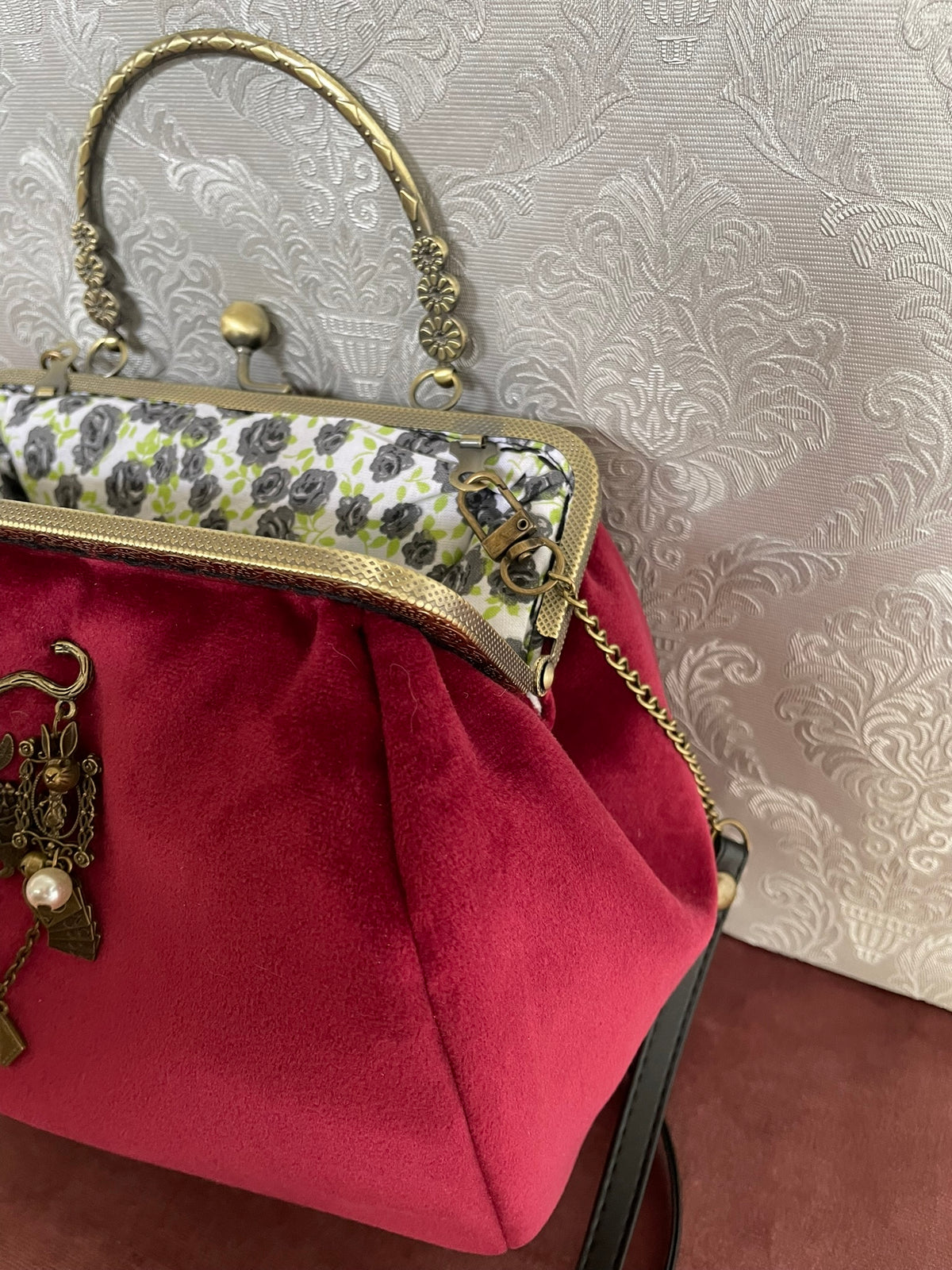 Vue de trois-quarts du sac rétro en velours rouge bordeaux avec broche Lapin d'Alice et doublure fleurie Le Comptoir de Suzanne