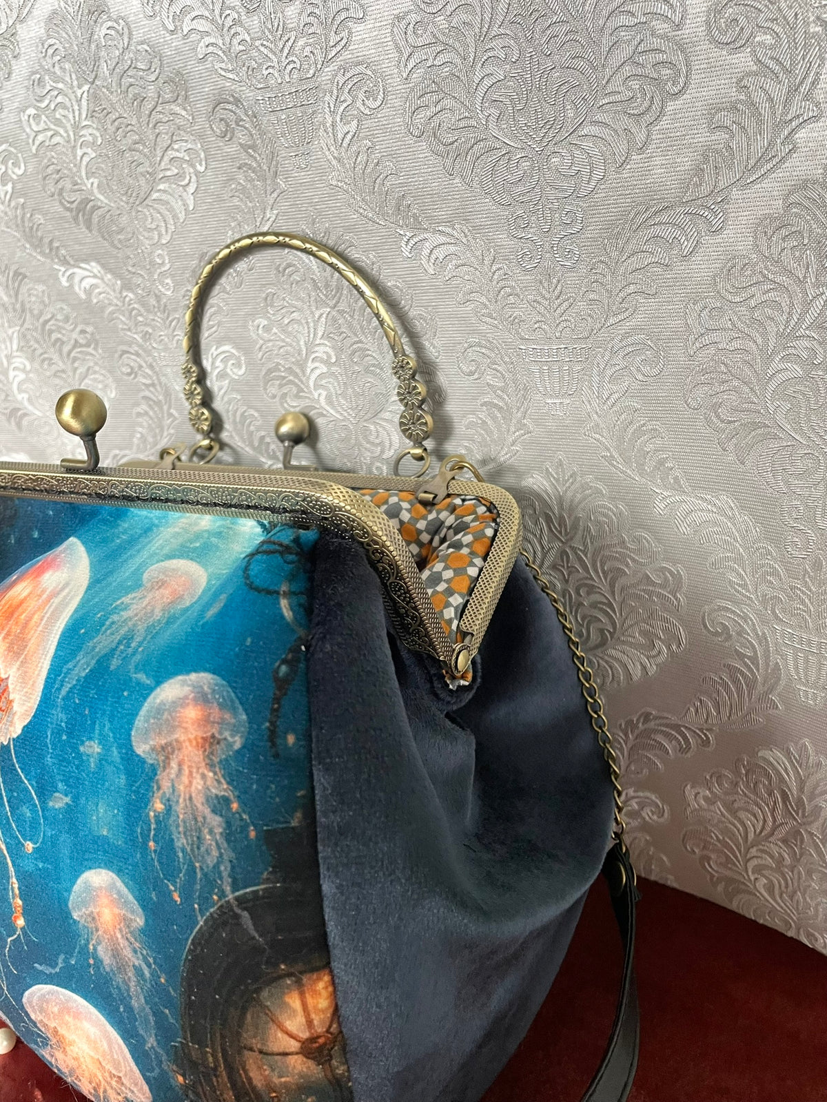 Gros plan fermoir effet bronze ciselé et doublure coton géométrique orange d'un sac retro méduses