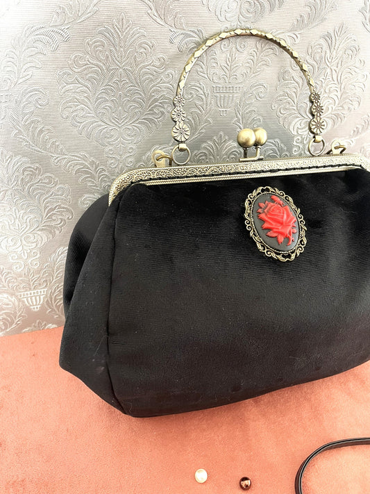 Vue de trois-quarts du sac rétro en velours noir montrant le volume et le fermoir kiss-lock bronze.