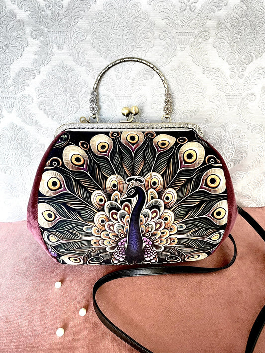 Détail de profil d'un sac à main rétro en velours lie de vin illustrant les plumes d'un paon royal avec fermoir bronze antique.