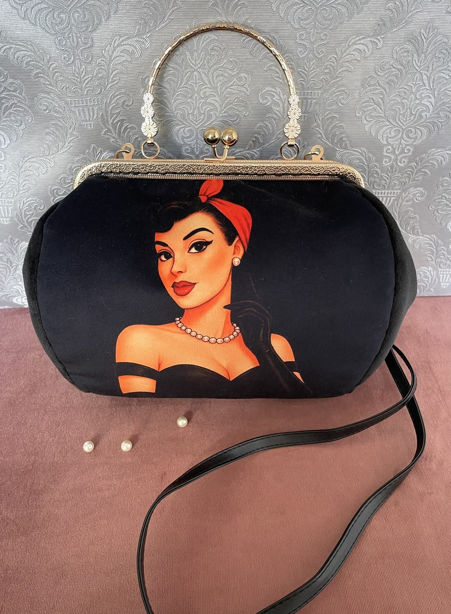 Détail de profil d'un sac à main rétro en velours noir illustrant une femme pin-up rétro avec foulard rouge et collier de perles.