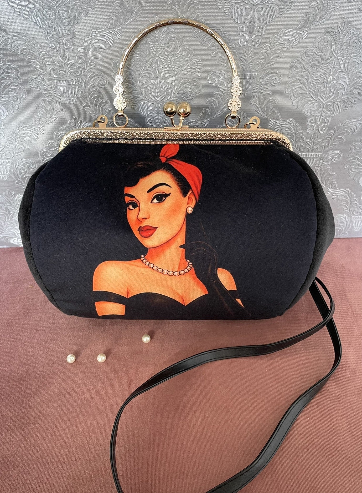 Détail de profil d'un sac à main rétro en velours noir illustrant une femme pin-up rétro avec foulard rouge et collier de perles.