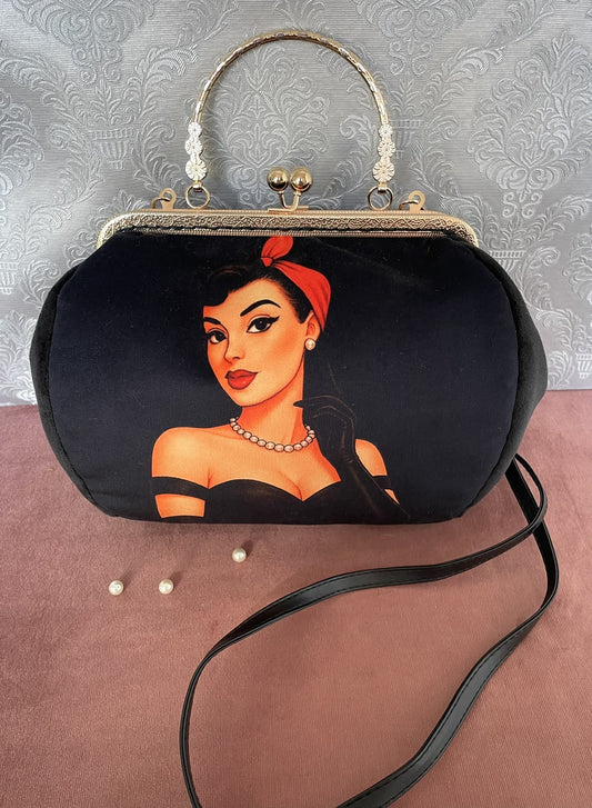 Détail de profil d'un sac à main rétro en velours noir illustrant une femme pin-up rétro avec foulard rouge et collier de perles.